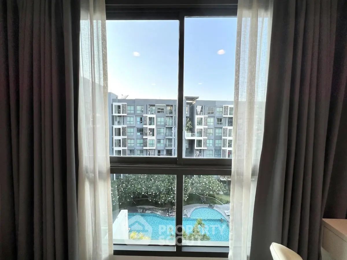 Modern apartment window view overlooking pool and residential building.