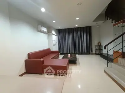 Spacious modern living room with red sofa and sleek staircase