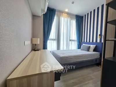 Modern bedroom with stylish striped wall and large window, featuring a cozy bed and wooden desk.
