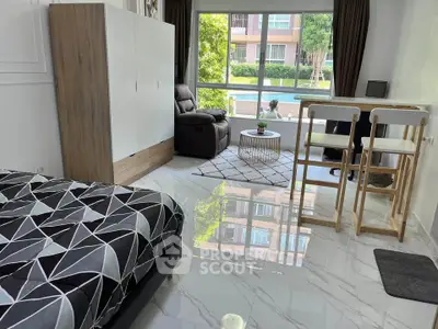 Modern studio apartment with pool view, featuring sleek furniture and natural light.