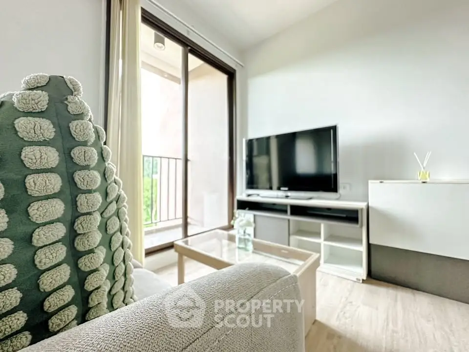 Modern living room with cozy sofa and large TV, featuring a balcony view.