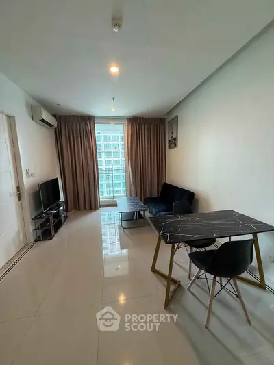 Modern living room with sleek furniture and large window offering city view.