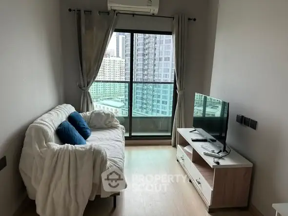 Cozy living room with city view, featuring a comfortable sofa and modern TV setup.