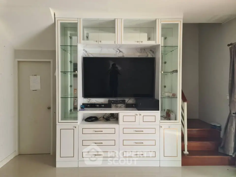 Elegant living room with built-in entertainment center and modern staircase