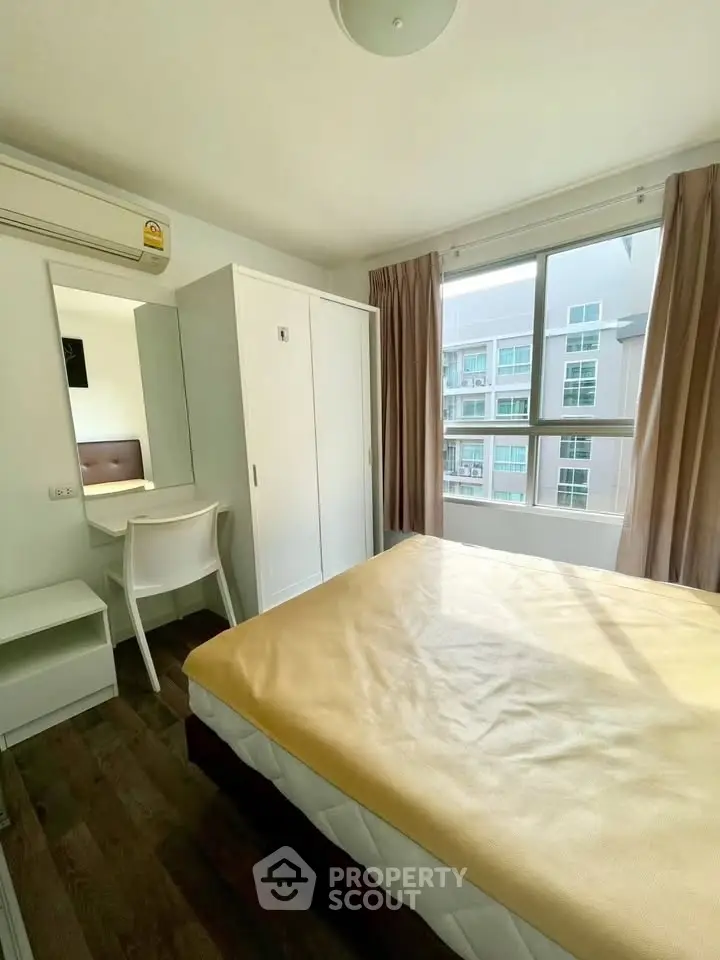 Bright bedroom with large window and modern furnishings in a stylish apartment.