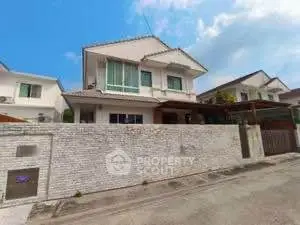 Charming two-story house with white brick fence and spacious driveway in suburban neighborhood.