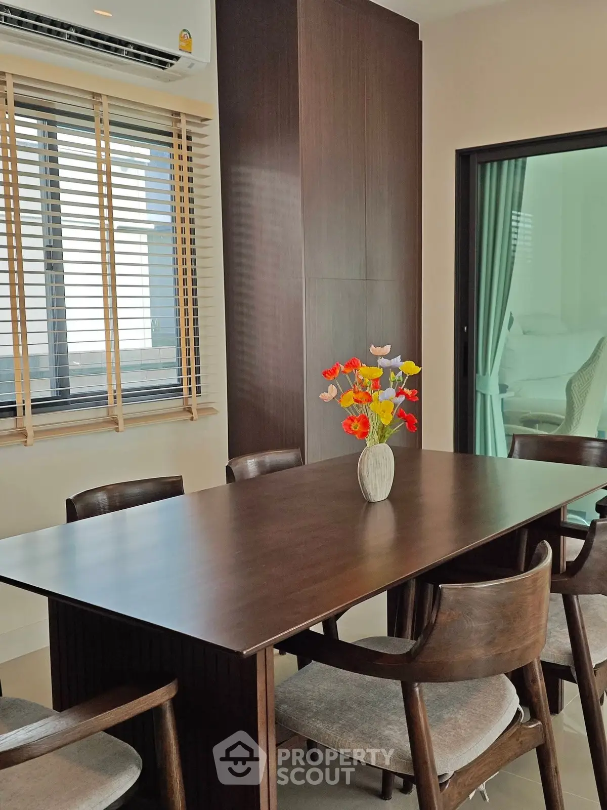 Elegant dining area with wooden table and chairs, featuring a vase of colorful flowers, perfect for modern living.