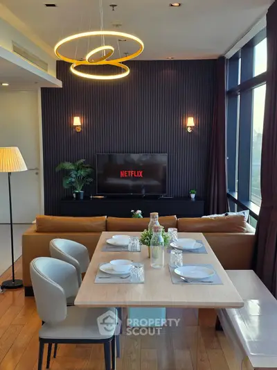 Modern living room with stylish lighting, cozy sofa, and dining area, perfect for entertainment and relaxation.