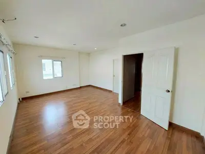 Spacious empty room with wooden flooring and white walls, ideal for customization.