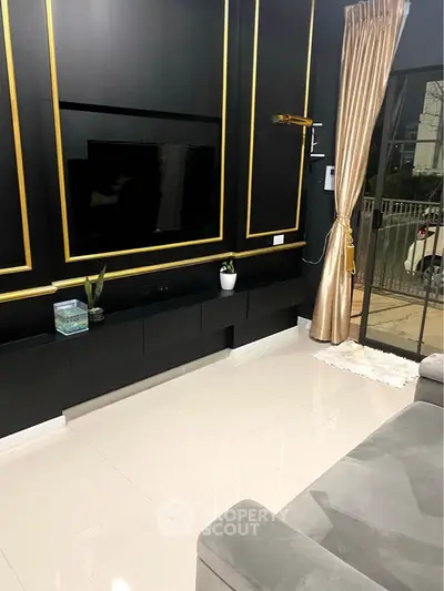 Luxurious living room with elegant black and gold decor, large TV, and plush seating.