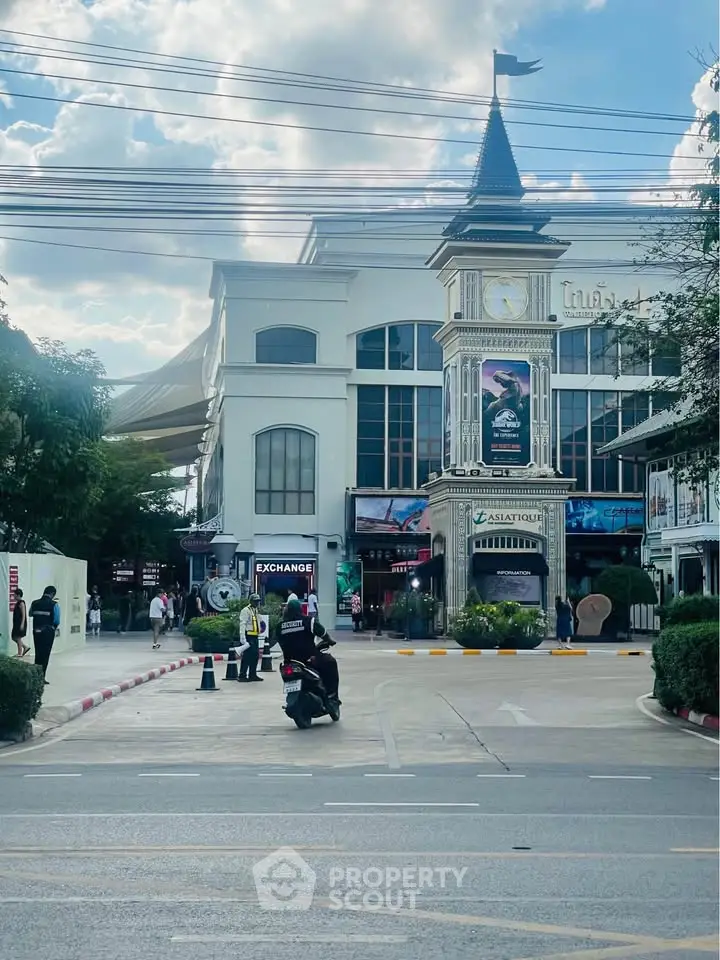 Charming clock tower building with shops and lush greenery, perfect for commercial real estate investment.