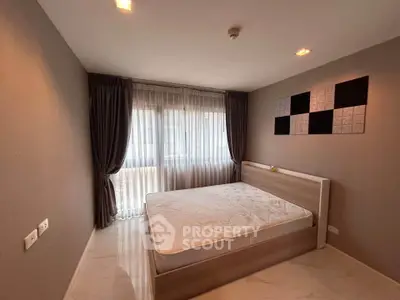 Spacious bedroom with large window and modern decor in a stylish apartment.