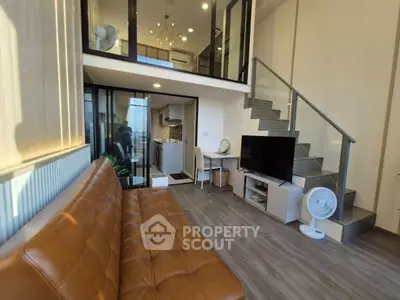 Modern loft apartment with open living area, stylish staircase, and cozy kitchen.