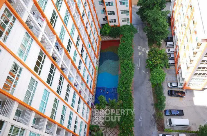 High-rise apartment view with pool and parking area, showcasing urban living amenities.