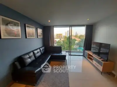 Modern living room with sleek black leather sofa and large TV, offering a stunning city view.