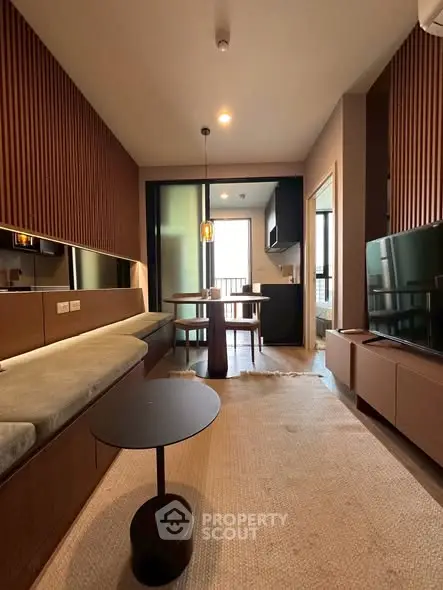 Modern living room with stylish decor and open kitchen layout, featuring wooden accents and cozy seating area.