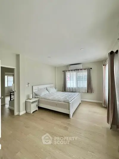 Spacious bedroom with elegant decor and natural light in modern apartment.