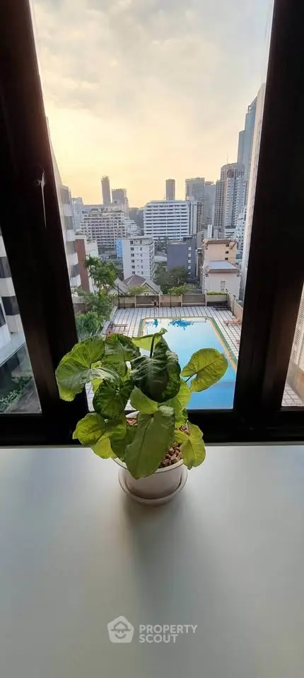 Stunning cityscape view from a high-rise window overlooking a pool, perfect urban living.