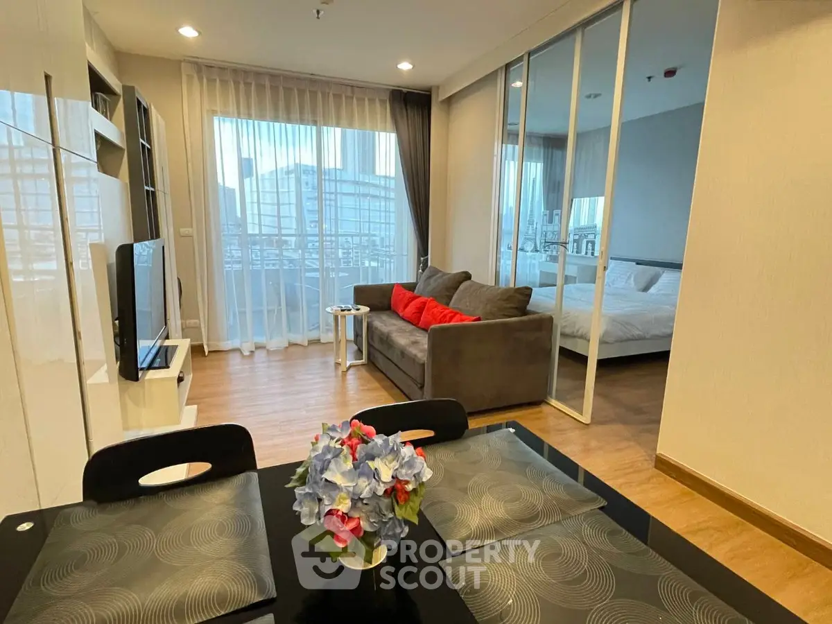 Modern open-plan living room with dining area and bedroom, featuring large windows and stylish decor.