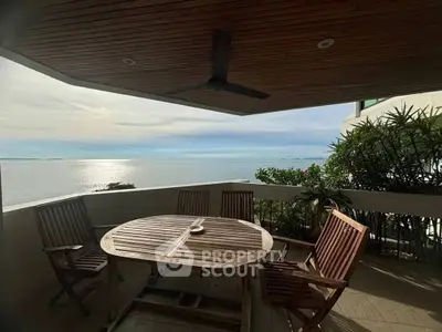 Stunning balcony with ocean view and wooden furniture, perfect for relaxation.