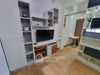 Modern living room with stylish shelving and TV unit, featuring wooden flooring and contemporary decor.