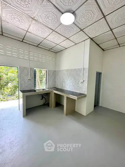 Spacious kitchen with modern design and open layout, featuring elegant ceiling tiles and ample natural light.