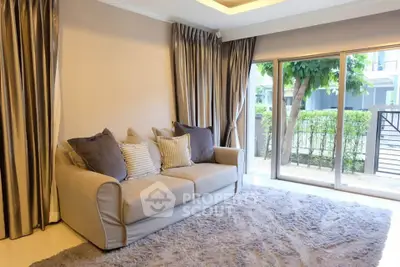 Spacious living room with plush sofa and large windows offering garden view