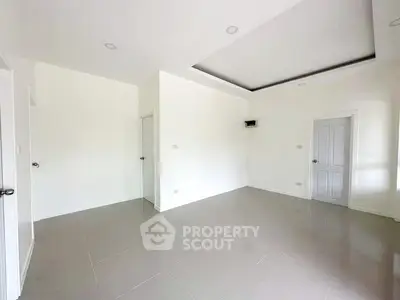 Spacious minimalist room with sleek tile flooring and modern recessed lighting.