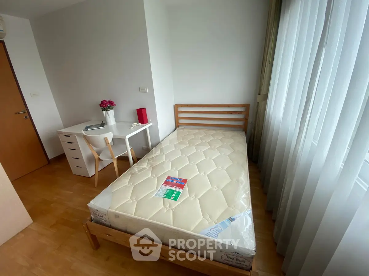 Cozy bedroom with single bed, desk, and large window for natural light.