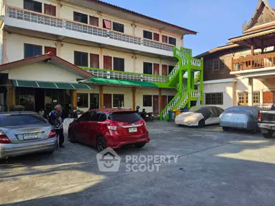 Spacious building exterior with parking area and vibrant green staircase
