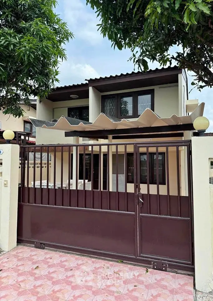 Charming two-story house with modern gate and lush greenery