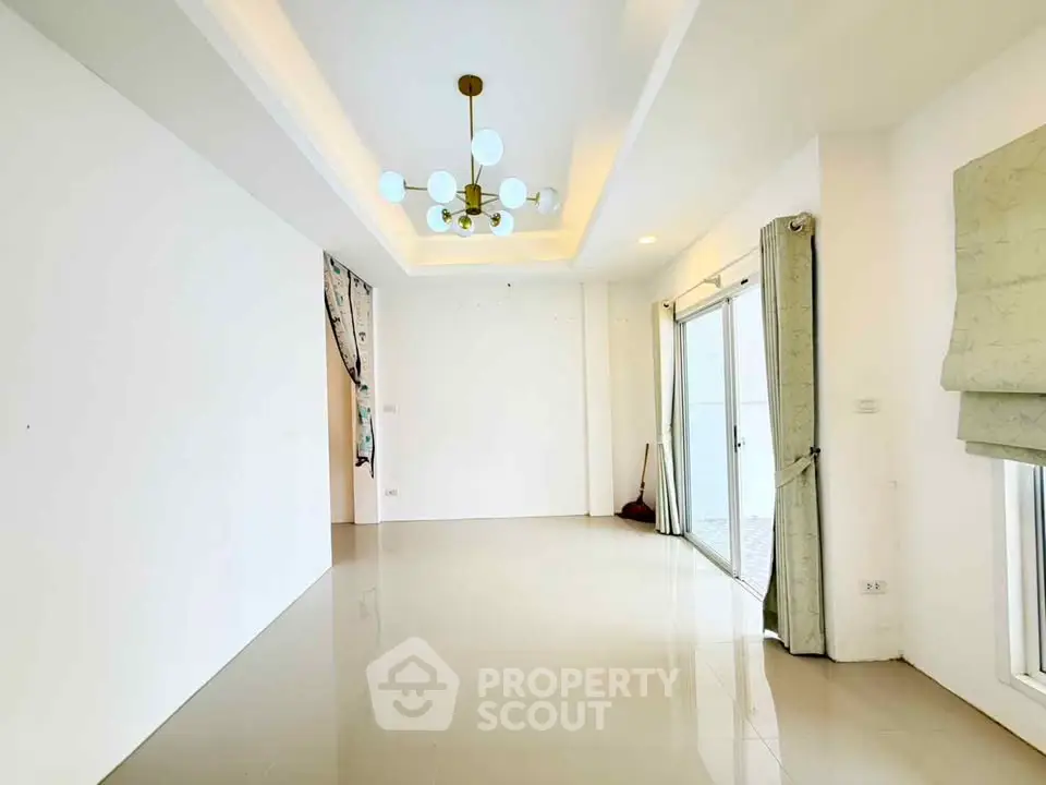 Spacious modern living room with elegant chandelier and large windows for natural light.