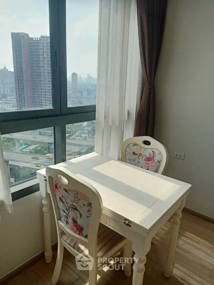 Charming dining nook with city view, featuring elegant white table and floral chairs by a large window.