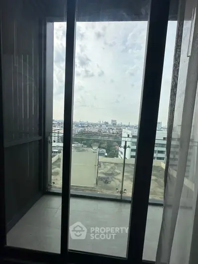 Stunning cityscape view from a modern apartment balcony with glass doors.