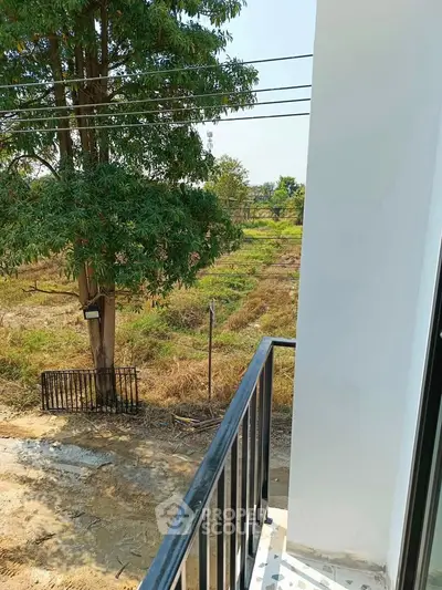 Charming balcony view overlooking serene countryside landscape with lush greenery and open fields.