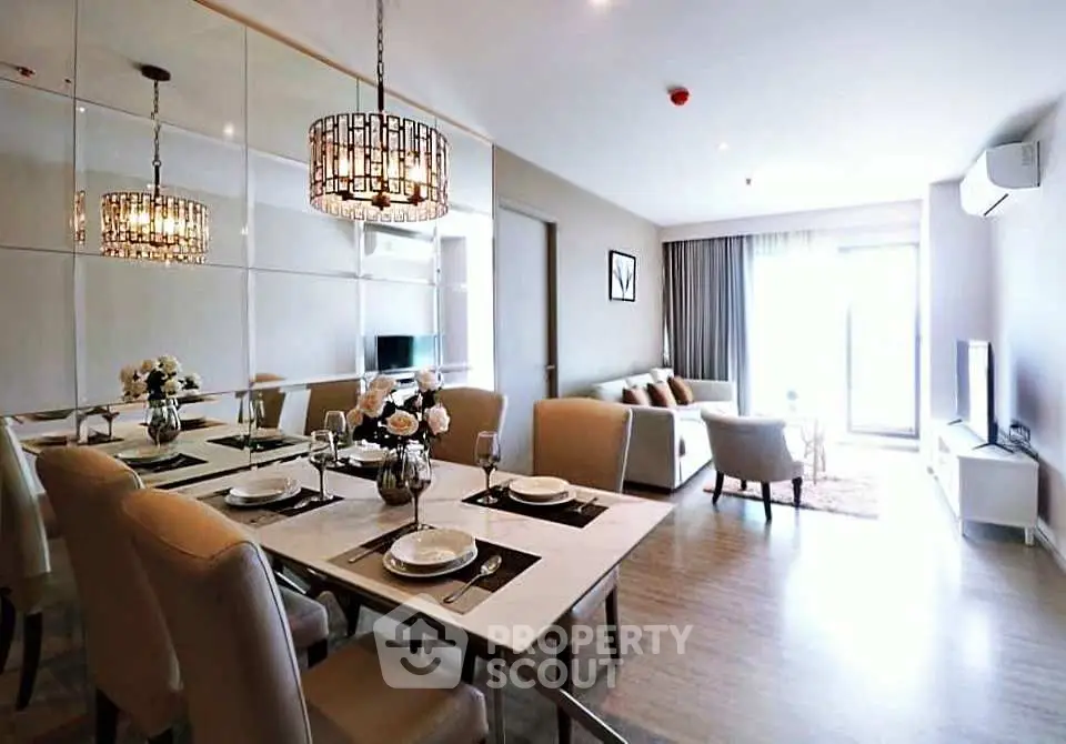 Elegant modern living room with dining area, stylish chandelier, and natural light from large windows.