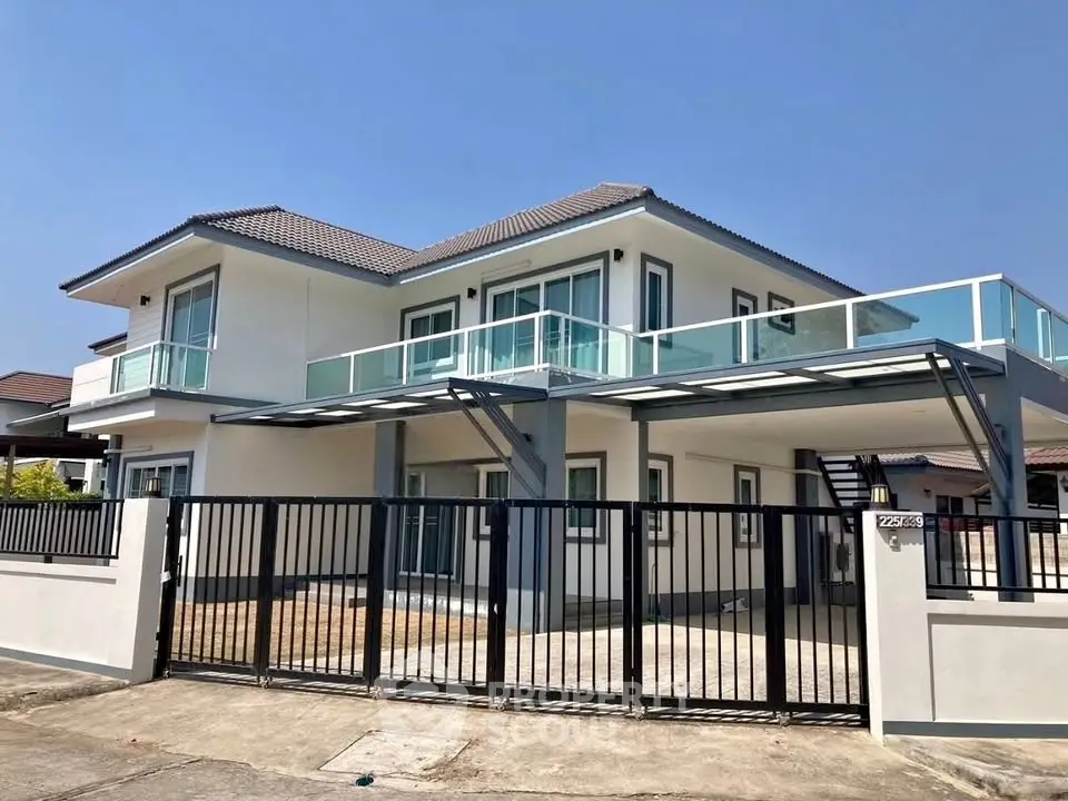 Modern two-story house with glass balcony and gated entrance