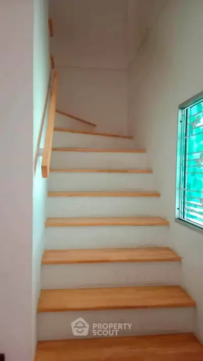 Modern wooden staircase with sleek handrail and window view