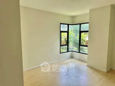 Bright empty room with large windows and wooden flooring