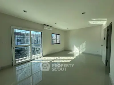 Spacious sunlit room with large windows and modern air conditioning unit.