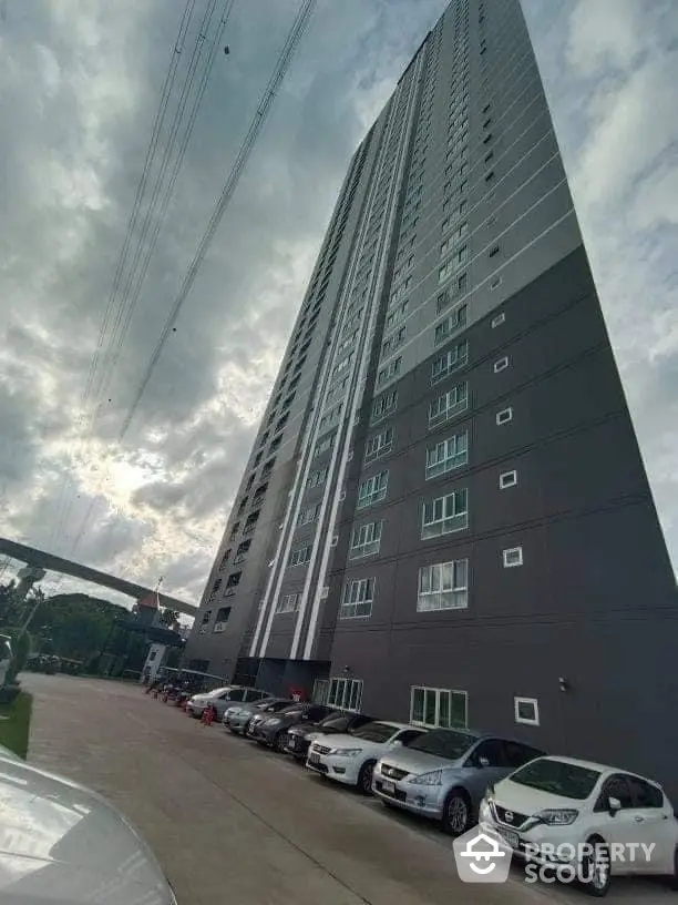 Modern high-rise apartment building with ample parking and urban skyline view.