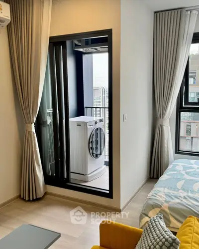 Modern apartment with balcony and washing machine, featuring stylish curtains and cozy furnishings.