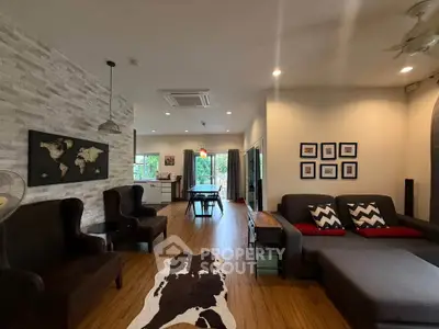 Spacious living room with modern decor and open layout, featuring stylish furniture and wooden flooring.