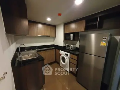 Modern kitchen with sleek cabinets, stainless steel fridge, and built-in washing machine.