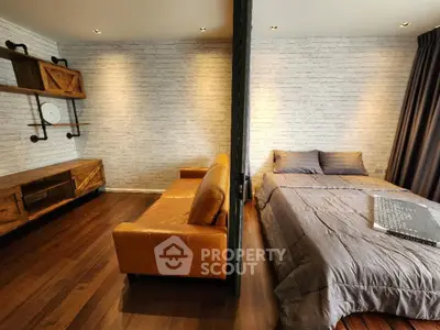 Chic modern bedroom with sleek wooden flooring, cozy bed, and stylish brick wall accents, perfect for urban living.