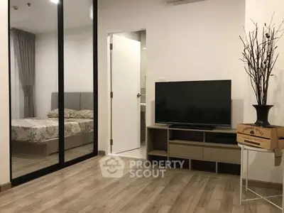 Modern living room with TV and view into cozy bedroom