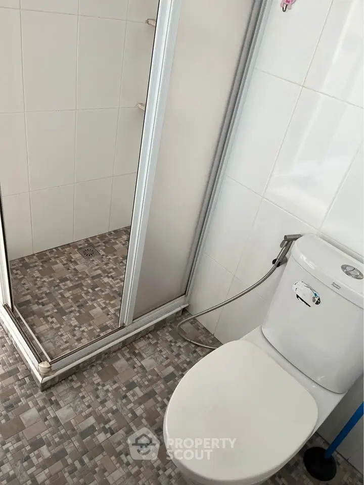 Modern bathroom with shower and toilet featuring sleek tile design.