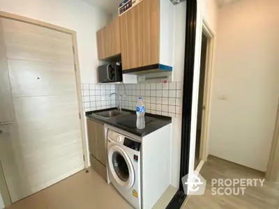 Compact modern kitchen with washing machine and wooden cabinets in cozy apartment