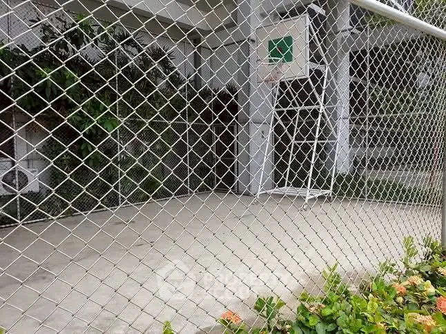 Outdoor basketball court with chain-link fence and greenery