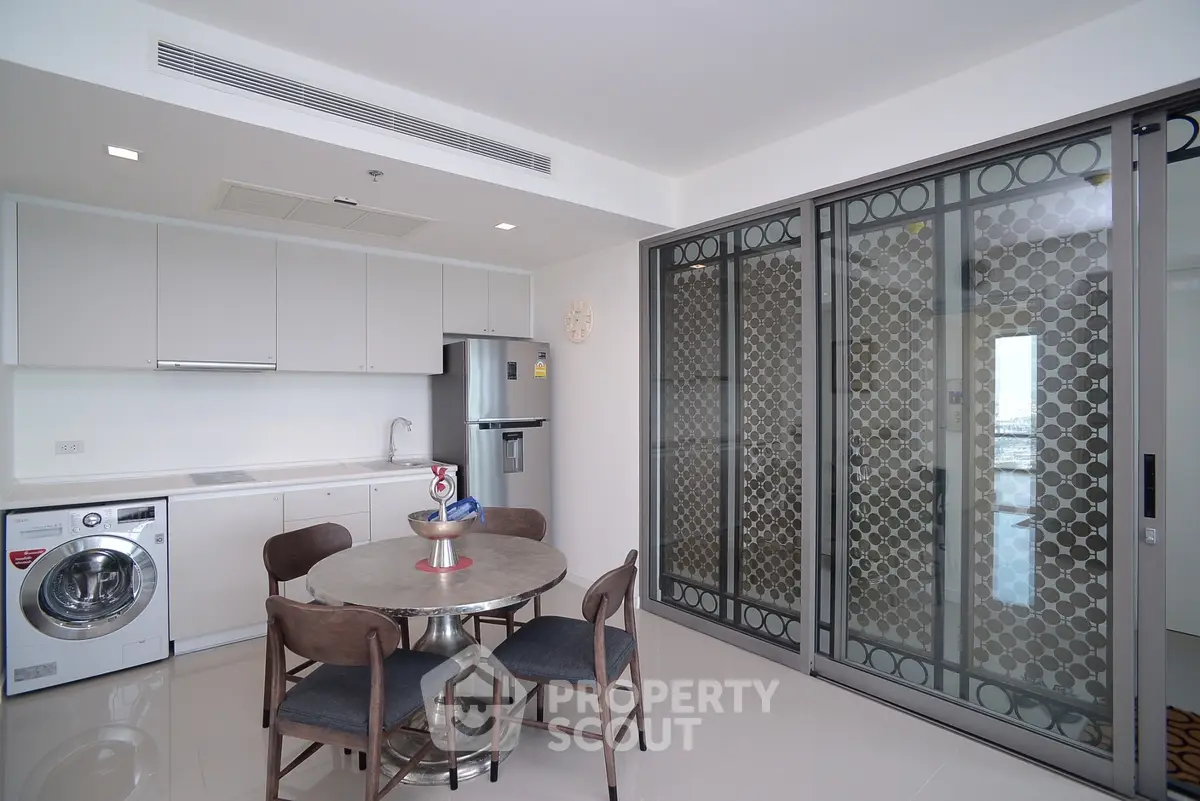 Modern kitchen with dining area and sliding glass doors in a stylish apartment.